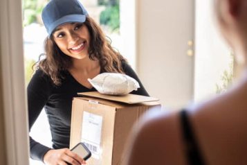 Woman with a cap smiling while delivering an order at a house