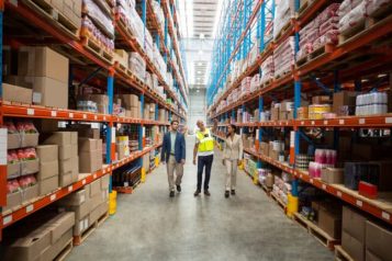 Warehouse employees walking through a warehouse filled with boxes