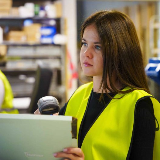 Returns Service Textblock 2 Young woman in yellow vest scanning the code of package