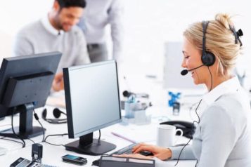 Customer service representatives with headset smiling at keyboard